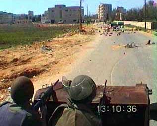Photo: Israeli soldiers behind impromptu barricades of garbage bins and barrels point their weapons at the students